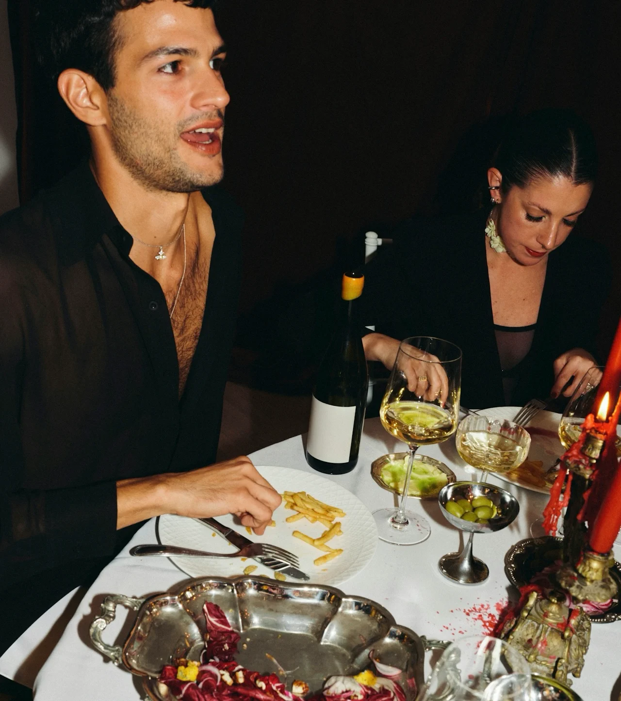 Man and woman eating at a candlelit dinner table.